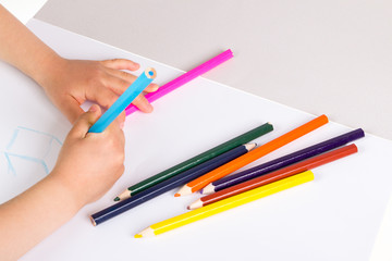 Child drawing in sketchbook  with color pencils.