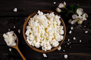 Cottage cheese in a bowl on wooden table. Style rustic.