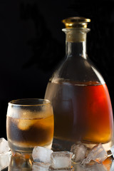 Glass with whiskey and a full whiskey bottle
