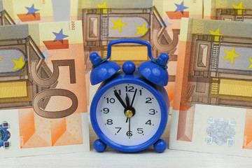 Miniature clock with banknotes in the background
