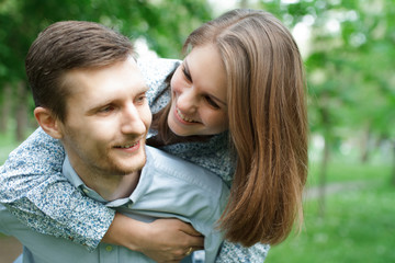 Fototapeta premium Loving couple in the park. He carries her on his shoulders