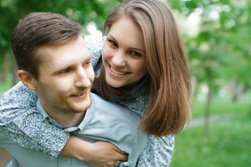 Fototapeta premium Loving couple in the park. He carries her on his shoulders