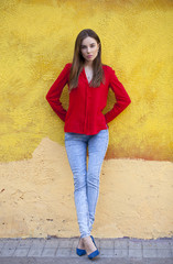 Young beautiful girl in blue jeans and a red shirt on the backgr