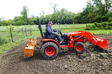Older Farmer Tilling His Garden With His Compact 4x4 Tractor © indyedge