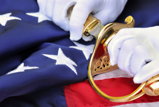 Symbols of a US Marine: white gloves, sabre, flag.
