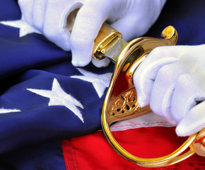 White gloves of a USMC officer holding saber over flag