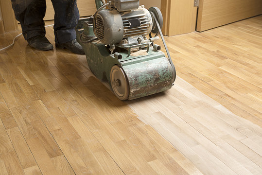 Wood floor polishing maintenance work by grinding machine.