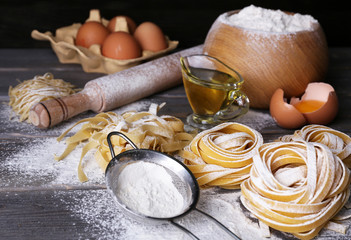 Raw homemade pasta and ingredients for pasta on wooden background