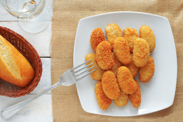 A fork and chicken nuggets served in a white bowl, top view
