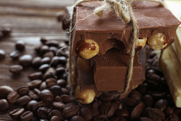 Stack of tied chocolate with coffee beans on wooden table, closeup