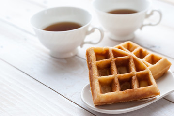 waffles and tea on white wooden board