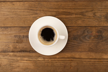 Cup of coffee on wooden table, top view