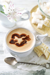 Cup of latte coffee art on wooden table, on light background