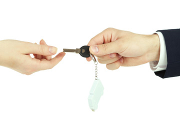 Male hand giving key with trinket to female hand isolated on white