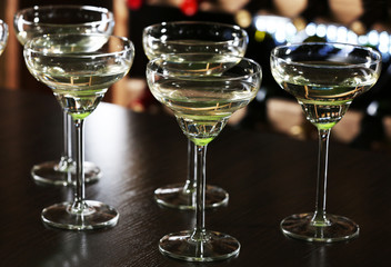 Glasses of cocktails on bar background