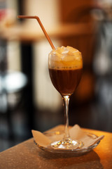 Glass of coffee with cream on table in cafe