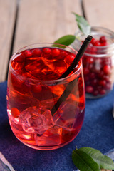 Compote with red currant in glassware on jeans cloth on wooden background