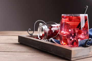 Compote with red currant on tray on wooden table, on dark background