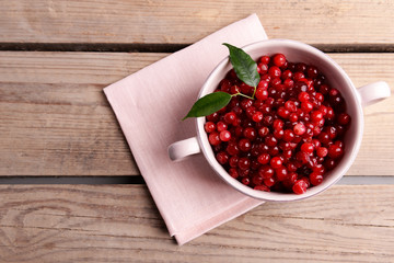 Red currant in bowl on wooden background