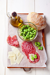 Italian snacks. salami, parmesan cheese, broad beans, fresh brea