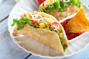 Tasty taco with tomato dip on plate on table close up