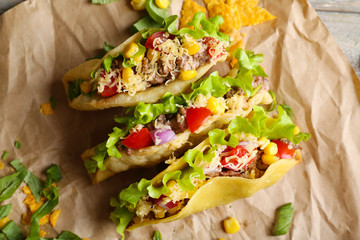 Tasty taco with greens on paper close up