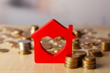 Model of house with coins on bright background