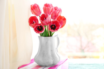 Beautiful bouquet of tulips in carafe on windowsill