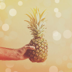 Man holding pineapple against beige background