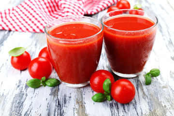 Glasses of tomato juice with vegetables on wooden background