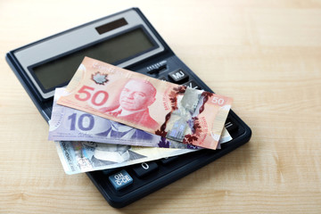 Calculator and Canadian dollars, on wooden table