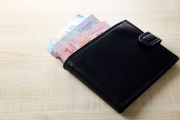 Male wallet with Canadian dollars on wooden table