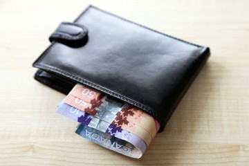 Male wallet with Canadian dollars on wooden table