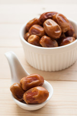 dates over spoon on wood background