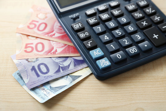 Calculator and Canadian dollars, on wooden table