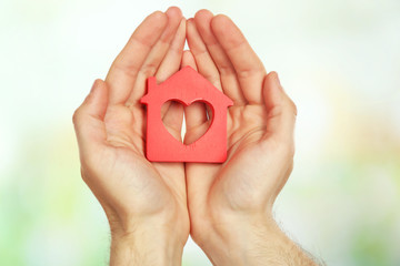 Female hands holding house on light blurred background