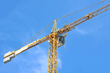 Yellow construction tower crane against blue sky