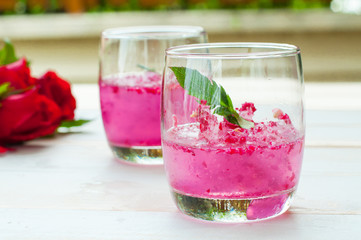 Pink Cocktail with fresh rose petals on wooden table