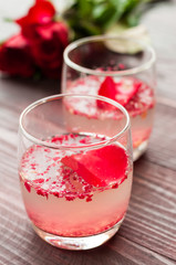 Pink Cocktail with fresh rose petals on wooden table