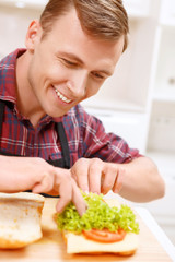 Obraz na płótnie Canvas Close up of man decorating bread with lettuce 