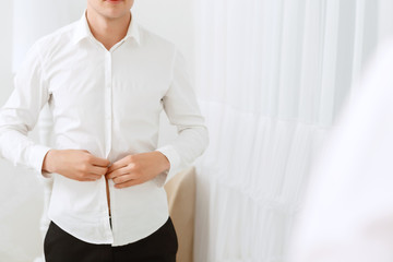 Close up of man buttoning white shirt