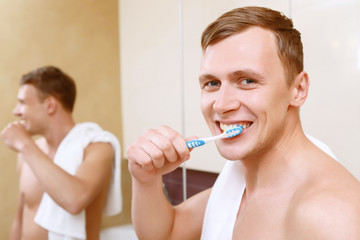 Man cleaning teeth in front of mirror