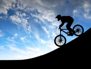 silhouette of the cyclist on downhill bike at sunset 