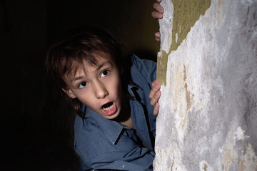 Obraz na płótnie Canvas Lonely little boy in a dark cellar