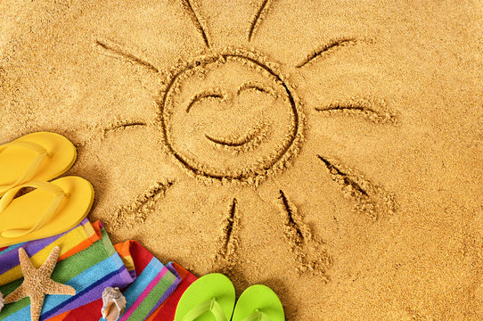 Summer beach smiling sun happy smiley face drawing drawn in sand with accessories holiday vacation photo