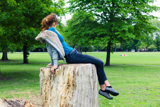 Young woman sitting on tree trunk in park