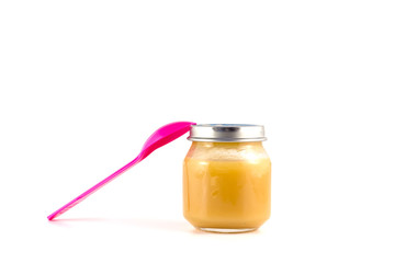 Baby fruit puree in the pot with a plastic spoon