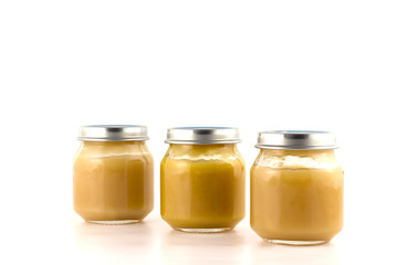Three glass jars of baby puree fruit stand nearby