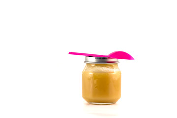 Baby fruit puree in the pot with a plastic spoon