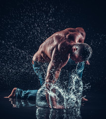 very muscular handsome athletic man striking with a hand on wate